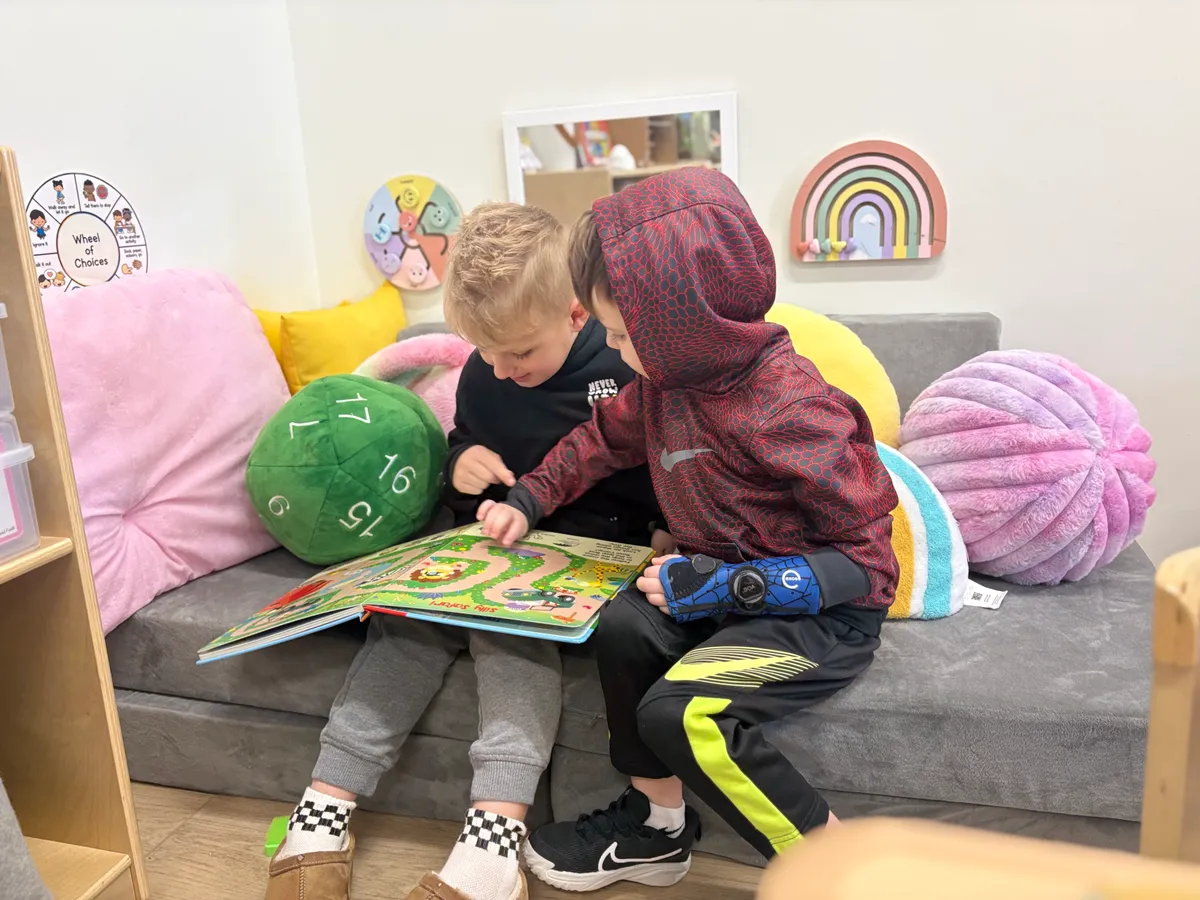 Two preschoolers reading together on a cozy couch at Spark Academy