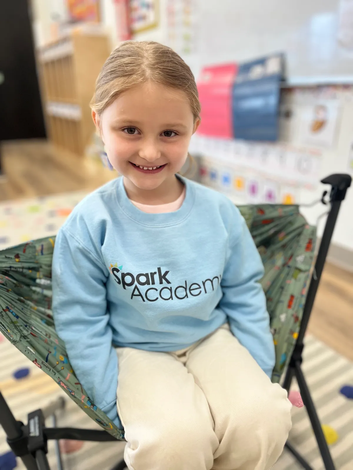 Spark Academy preschool student smiling in branded sweatshirt